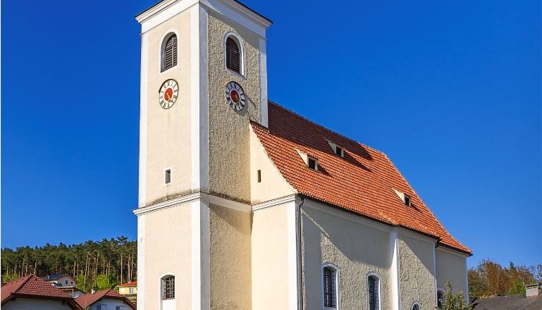 Pfarrkirche Hollenthon mit Zwiebelturm und blauen Himmel.