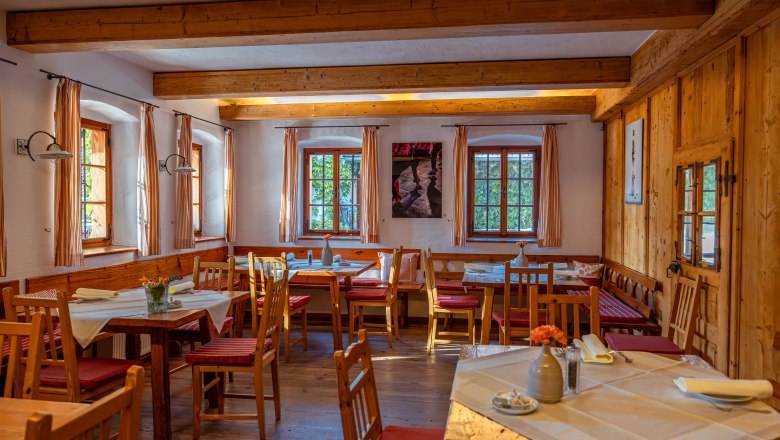 Gemütlicher Gastraum mit Holzmöbeln und gedeckten Tischen.