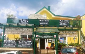 Gelbes Gasthaus mit grüner Beschilderung von Tagesangeboten