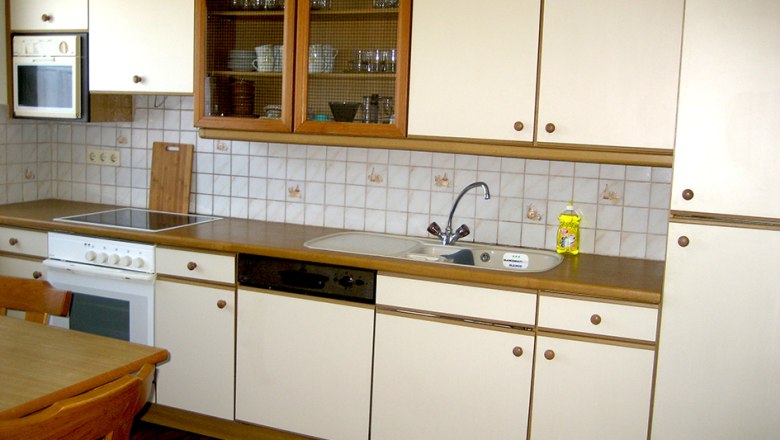 Küchenzeile mit weißen Schränken, Herd, Spüle und Geschirrspüler.