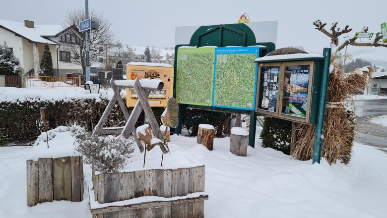 Winterlicher Wanderstartplatz mit Infotafeln und Schnee vor dem Krumbacherhof.