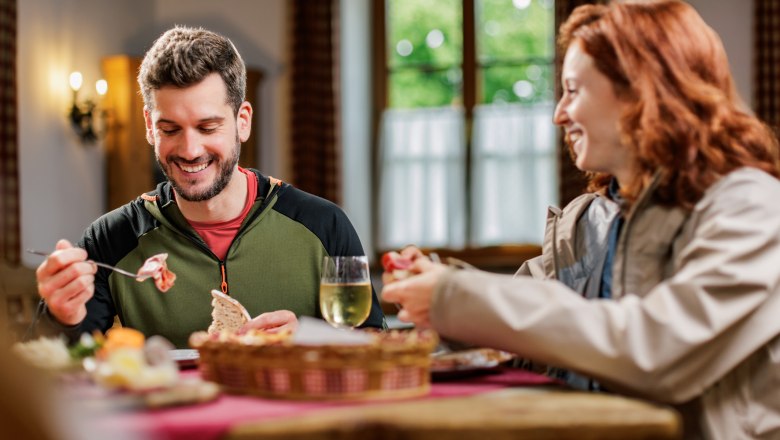 Ein Mann und eine Frau teilen sich eine Brettljause in einem Heurigen