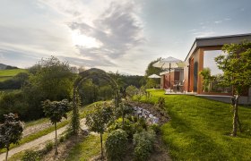 Moderne Unterkunft in grüner Landschaft mit Sonnenschirmen und Garten.