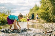 Ein Kind spielt mit Wasser und Steinen in einem Bach