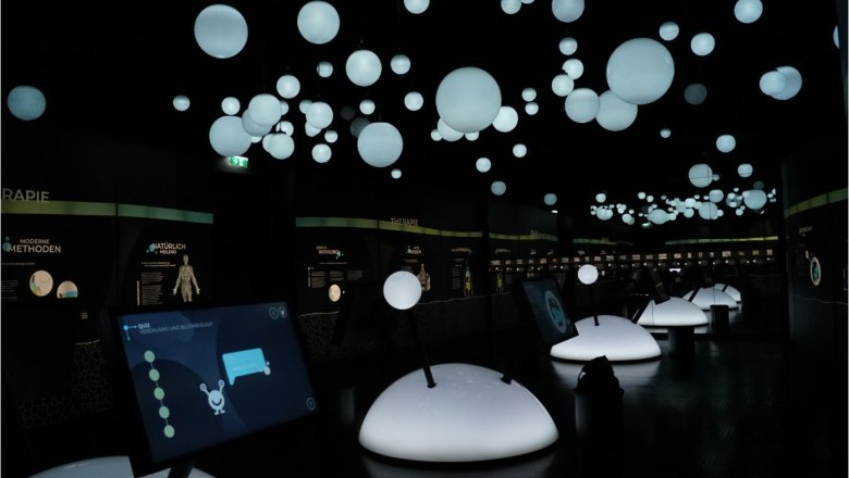 Dunkler Ausstellungsraum mit leuchtenden Kugeln und interaktiven Bildschirmen.