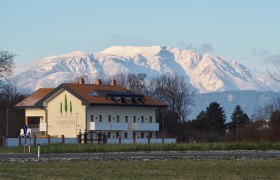 Geb&auml;ude mit der Aufschrift 'mattone apartments' vor schneebedecktem Berg im Hintergrund.