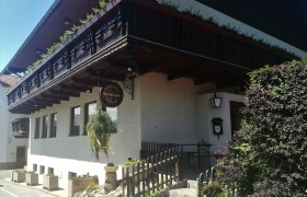 Traditionelles Geb&auml;ude mit Holzbalkon und Schild mit der Aufschrift "Mostschank".