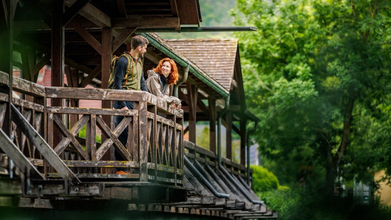 Ein Paar auf einer Ausbuchtung einer Holzbrücke, die über die Leitha führt