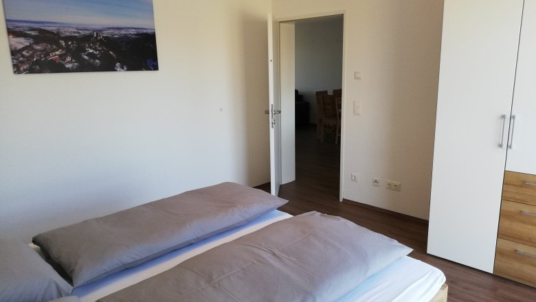 Modernes Schlafzimmer mit Doppelbett, wei&szlig;em Kleiderschrank und Landschaftsbild an der Wand.