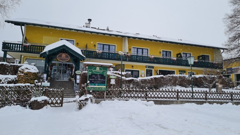 Gelbes Gebäude im Schnee mit grüner Veranda und Eingang.