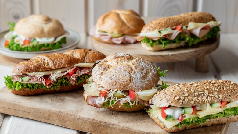 Verschiedene belegte Br&ouml;tchen auf Holzbrett arrangiert.