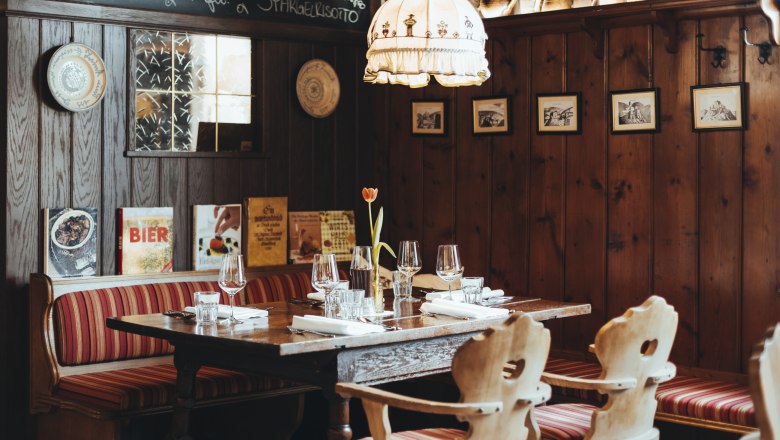 Gemütliches Restaurant mit Holzwänden, rot gestreiften Sitzbänken und gedecktem Tisch.