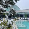 Au&szlig;enbereich der Therme Linsberg Asia mit schneebedeckten B&auml;umen und Liegest&uuml;hlen, neben einem Pool.