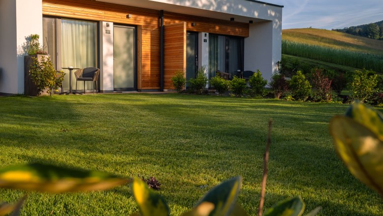 Modernes Gebäude mit Holzverkleidung und Terrasse in grüner Landschaft.