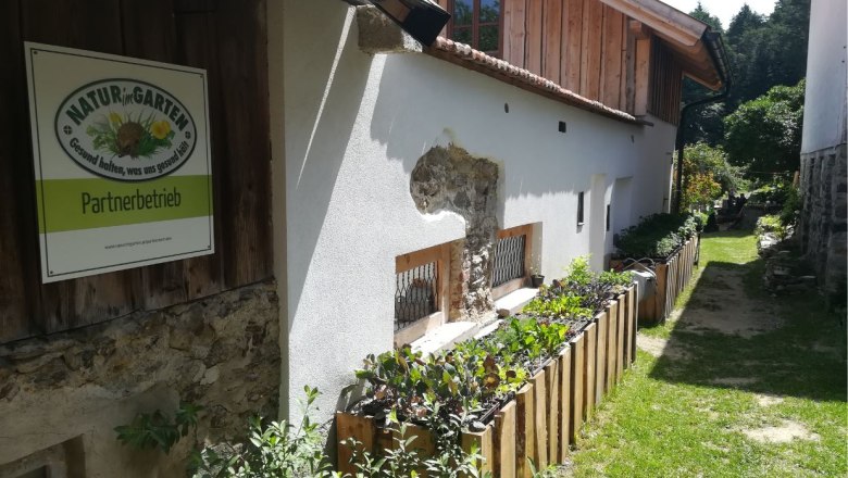 Au&szlig;enansicht eines Geb&auml;udes mit Schild 'Natur im Garten Partnerbetrieb'.