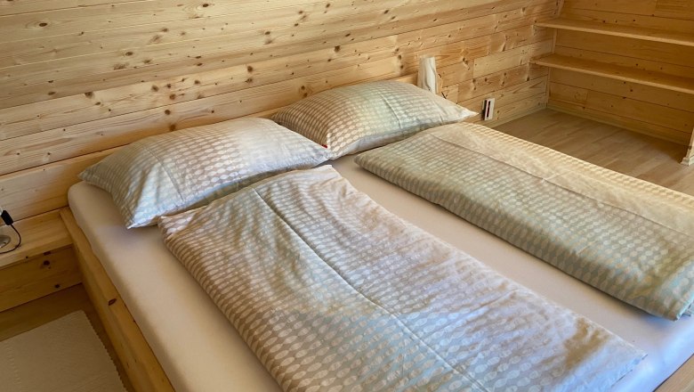 Doppelbett in einem Zimmer mit Holzverkleidung.