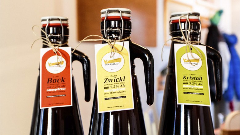 Drei Bierflaschen mit Etiketten von Wolfsbräu: Bock, Zwickl und Kristall.
