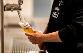 Eine Person zapft Bier in ein Glas mit der Aufschrift "Schwarzbräu".