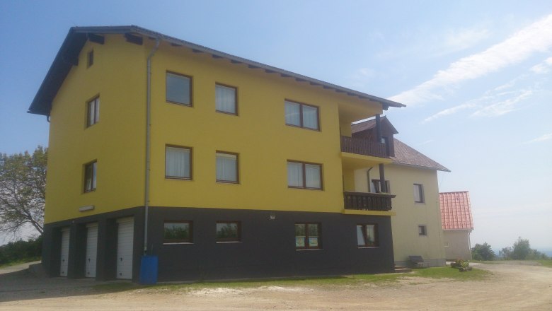 Gelbes Geb&auml;ude mit mehreren Fenstern und Balkonen, blauer Himmel im Hintergrund.