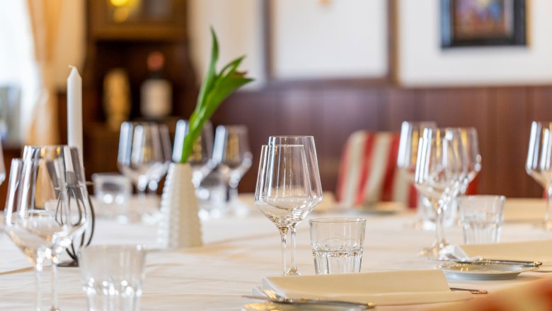 Eleganter Tisch im Hotel Post mit Weingläsern, Kerze und Blumenvase.
