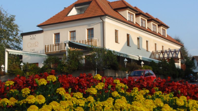 Hotel Geier in Bad Schönau mit Blumenbeet im Vordergrund.