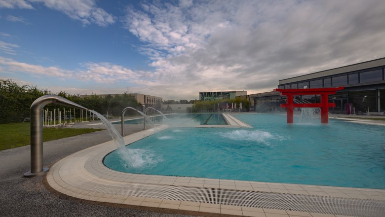 Außenpool im Hotel & Spa Linsberg Asia mit Wasserfontänen und rotem Torii.