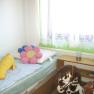 Kinderzimmer mit Bett, Plüschtieren und Spielzeugpferd.