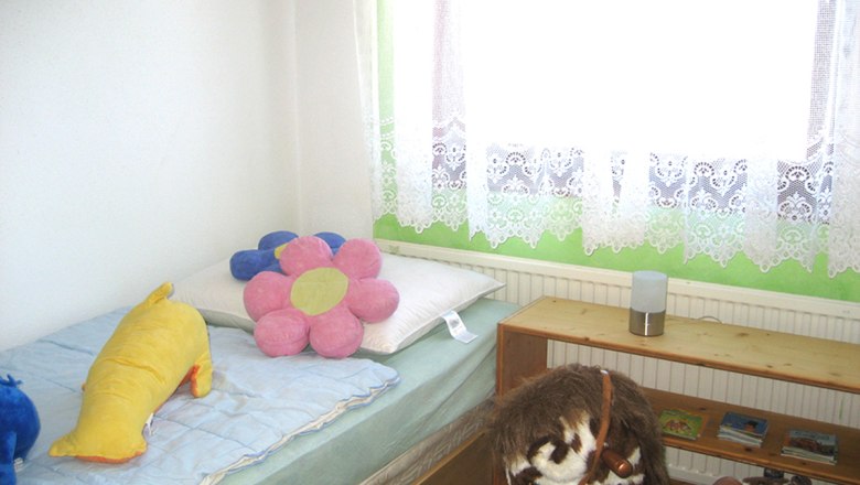 Kinderzimmer mit Bett, Plüschtieren und Spielzeugpferd.