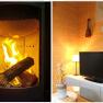 Ein brennender Kamin und ein gemütliches Wohnzimmer mit Fernseher, Lampe und Dekoration.