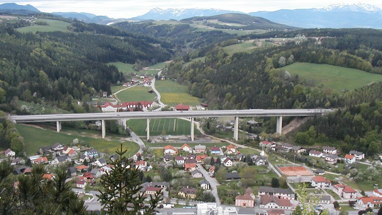 Panoramablick auf die Gemeinde Warth mit Br&uuml;cke und umliegenden H&uuml;geln.