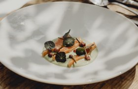 Ein Teller mit Lachsforelle, Kapuzinerkresse-Creme, Kapuzinerkresseblättern und Schnittlauchknospen.