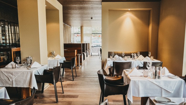 Elegantes Restaurant mit gedeckten Tischen und Ledersesseln.