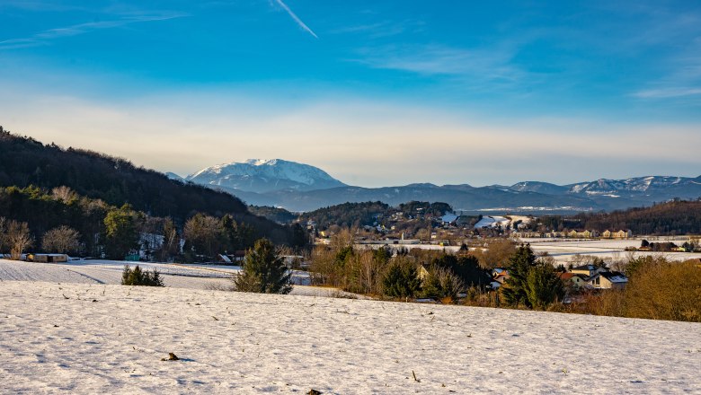 Winterlandschaft mit schneebedeckten Feldern und Schneeberg, im Hintergrund in Bad Erlach.