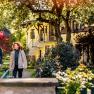Ein Mann und eine Frau in Wanderkleidung gehen durch den grünen, gepflegten Garten der Pension Hendling