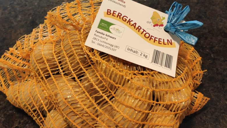 Ein Sack mit Bergkartoffeln auf dunkelgrauem Hintergrund.