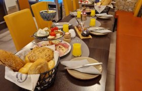 Fr&uuml;hst&uuml;ckstisch mit Br&ouml;tchen, Aufschnitt und Orangensaft in einem Caf&eacute;.