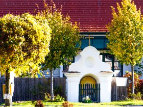 Kleine, wei&szlig;e Kapelle neben herbstlichen B&auml;umen