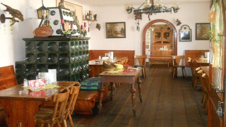 Innenansicht eines traditionellen österreichischen Heurigen mit Holzmöbeln und Kachelofen.