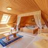 Gemütliches Schlafzimmer mit Holzwänden, einem Bett, Sofa und Dachfenster.