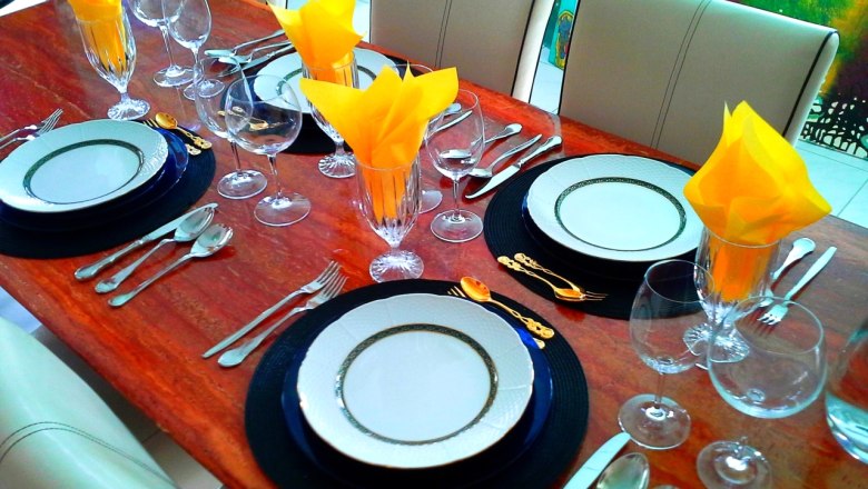 Eleganter Esstisch mit Geschirr, Besteck und gelben Servietten.