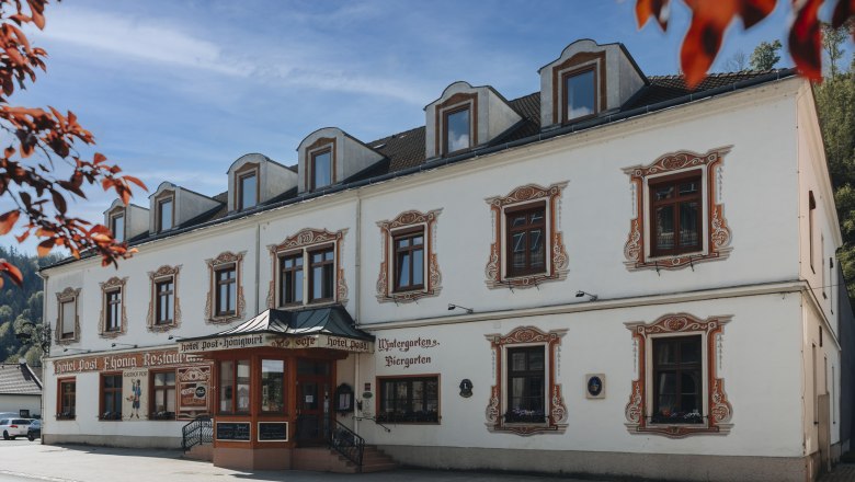 Historisches Gebäude mit dekorativen Fensterrahmen und Schildern für Hotel und Restaurant.