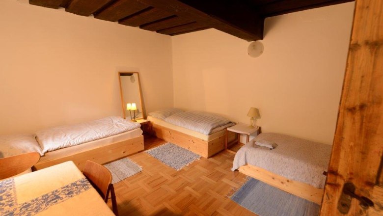 Dreibettzimmer mit Holzm&ouml;beln und Parkettboden.