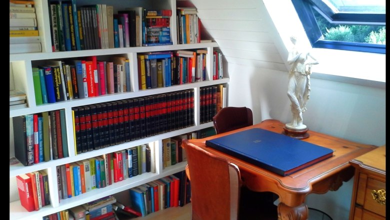 Ein gem&uuml;tlicher Arbeitsbereich mit B&uuml;cherregal, Schreibtisch und Statue.