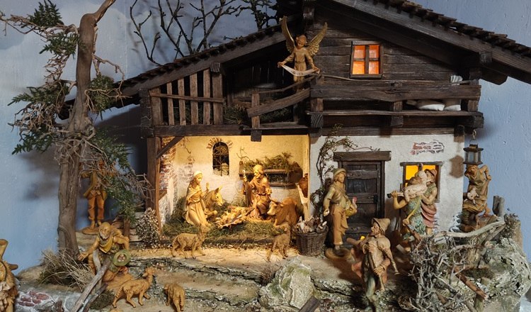 Detailreiche Weihnachtskrippe mit Figuren und Tieren in einem rustikalen Stall.