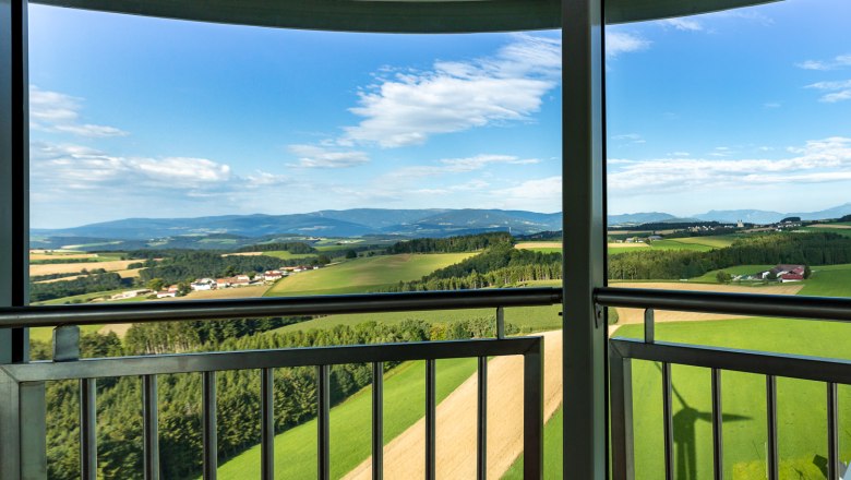 Aussicht von der Kanzel des Windrades aus auf eine gr&uuml;ne Landschaft mit Feldern und H&uuml;geln unter blauem Himmel.